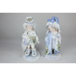 A pair of Continental porcelain figures of two children playing at dressing up, each on circular