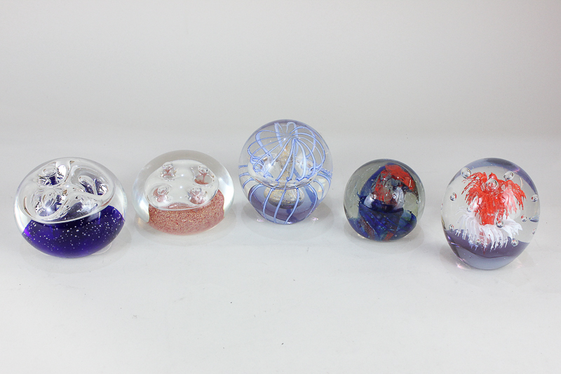 A collection of five glass paperweights with swirling polychrome and bubble decoration, to include a