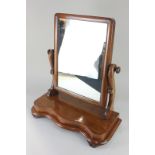 A mahogany dressing table mirror, with rectangular adjustable mirror, on serpentine shaped base,