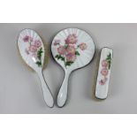 A George VI silver and enamel three-piece dressing table set of hand mirror, hair and clothes brush,