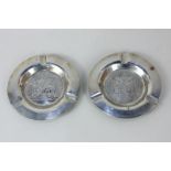 A pair of Continental white metal ashtrays marked NOK 830, one engraved with a double headed