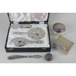 A modern silver backed four-piece dressing table set embossed with masks, scrolling foliage and