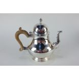 An Elizabeth II silver Queen Anne style teapot, makers Wakely & Wheeler, London 1967, with wooden