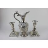 A silver plated ewer with embossed mask head design, together with a pair of candlesticks