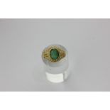 A carved emerald ring, the oval cabochon bead set in a pierced mount in 18ct yellow gold