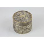 A Chinese white metal circular box embossed with dragons chasing the flaming pearl marked KK 90 to