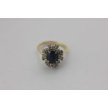 A sapphire and diamond cluster ring, the oval cut stone within a two-row diamond border, in 18ct