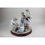 A large Nao porcelain figure group of boys playing cards, on wooden base, 30cm high