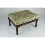 A 19th century mahogany upholstered footstool with carved frieze and floral roundels, on fluted