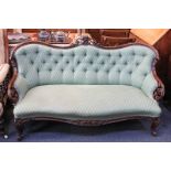 A Victorian button back settee with pierced and carved scrolling foliate show frame, with green