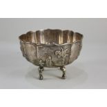 A Chinese white metal bowl with raised four-panel design including figures, birds in cherry