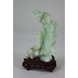 A Chinese carved jade figure of a woman holding flowers, on carved wood stand, figure 17.5cm