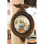 A Regency style gold painted circular convex wall mirror with eagle pediment, ball finials and