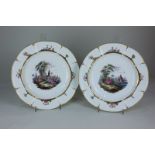 A pair of Continental porcelain cabinet plates decorated with lakeside vignettes of figures before a