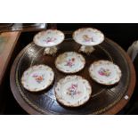 A Continental porcelain part dessert service decorated with flower sprays within a pierced maroon