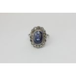 A sapphire and diamond cluster ring, the oval cut stone within a border of sixteen round diamonds in