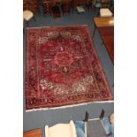A Turkish wool carpet, with central geometric design within multi line border, on red ground,