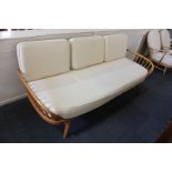 An Ercol three-seat settee with panel back and spindle arms