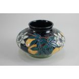 A Moorcroft pottery 'passion fruit' vase with floral decoration on dark blue ground, of squat