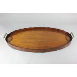A Sheraton style mahogany oval butler's tray with undulating gallery and brass handles, painted with