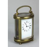 A brass cased oval carriage clock, the white enamel dial with Roman numerals, the movement stamped