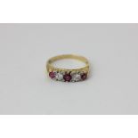 A ruby and diamond five stone ring, claw set with graduated circular cut stones in platinum on