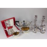 A silver plated three-piece tea set, a sugar caster, a sauce boat, a pair of candlesticks, and a