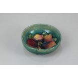 A Moorcroft pottery clematis circular pin dish decorated with orange and red flower on green and