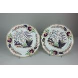A pair of early 19th century Derby porcelain plates decorated with plants in polychrome colours with