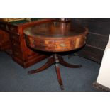 A George III style drum top library table with leather inset top above frieze drawer and series of