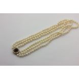 A three-row cultured pearl necklace strung on a 9ct gold, garnet and pearl clasp