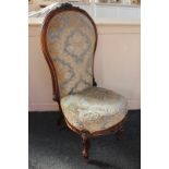 A Victorian nursing chair with carved floral designs, blue and gold floral upholstery, on