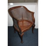 A stained mahogany framed Beregere elbow chair with cane back and seat, on claw and ball feet,