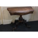 A Victorian walnut serpentine shaped card table with fold-over top on baluster stem and four