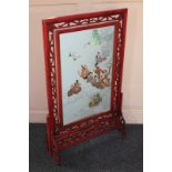 A Chinese glazed fire screen with revolving rectangular blue silk needlework panel depicting figures