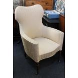 A Victorian cream upholstered armchair with shaped panel back and continuous arms over a