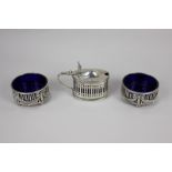 A pair of George V silver circular salts with pierced swag and bow design and blue glass liners,