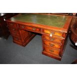 A large oak pedestal desk, the rectangular top with green leather inset above an arrangement of