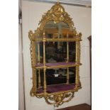 A 19th century giltwood and gesso set of wall shelves with mirrored back, the domed top with central