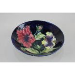 A Moorcroft pottery circular lily dish decorated with red and yellow flowers on blue ground, 19cm