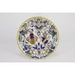 A German faience plate decorated with heraldic crests, mythical figures and animals, later label