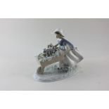 A Lladro porcelain figure of a girl pushing a wheelbarrow filled with flowers and puppies, 22.5cm