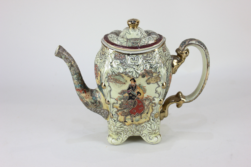 A Japanese Satsuma ware teapot decorated with panels of figures on horseback amongst foliate