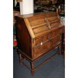 An early 20th century oak bureau, the fall front revealing interior of drawers and pigeon holes,