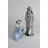 Two Nao porcelain figures, a child and puppy hiding within oversized raincoat, and girl with bird,