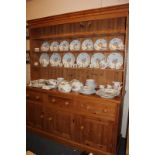 A large pine dresser, the matched top section with three shelves and closed panel back, the base