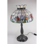 A Tiffany style table lamp, the leaded glass shade with tulip design, on bronzed base modelled as