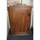 A George III hanging corner cupboard with scroll shaped cornice, single panelled door enclosing