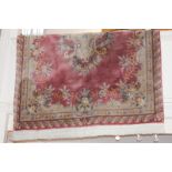 A Chinese wool rug with central floral design on pink ground 183cm by 266cm