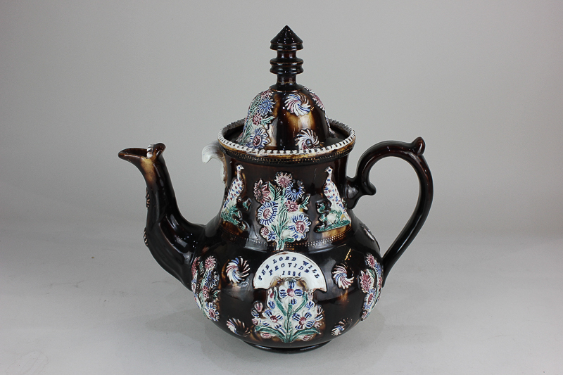 A large Victorian bargee's teapot decorated in light relief with polychrome decoration of flowers